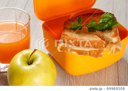 Yellow lunch box with toasted slices of bread, cheese and parsley, green apple. 69969508