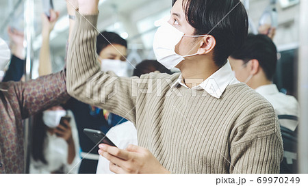 Traveler wearing face mask while using mobile phone on public train Traveler wearing face mask while using mobile phone on public train 69970249