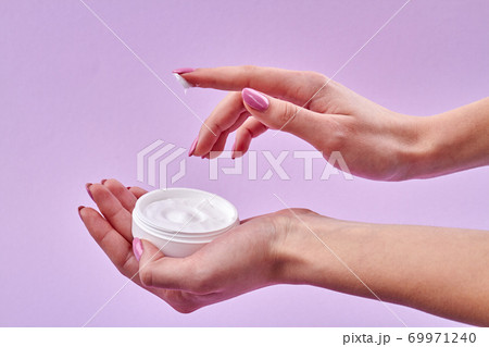 Close-up female hand applying skin cream. 69971240