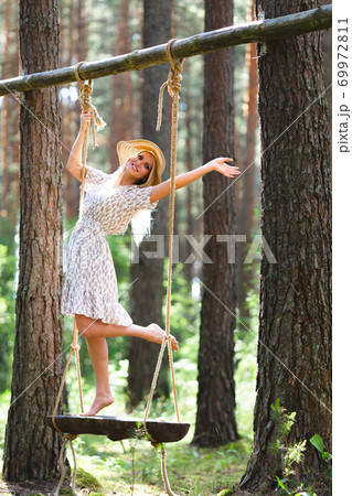 Blond woman with slender beautiful naked legs standing with on a rope swing 69972811