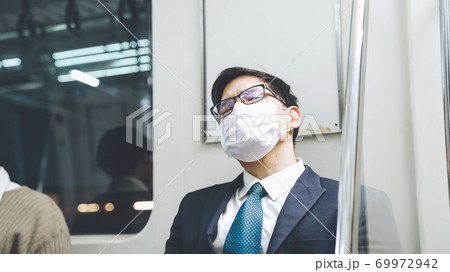 Young man wearing face mask travels on crowded subway train Young man wearing face mask travels on crowded subway train 69972942