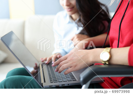 Woman in wheelchair working on laptop close-up 69973998