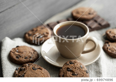 Coffee cup with cookies and chocolate on wooden table background. Mug of black coffee with chocolate cookies. Fresh coffee beans. Coffee cup with cookies and chocolate on wooden table background. Mug of black coffee with chocolate cookies. Fresh coffee beans. 69974896
