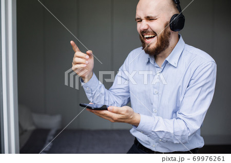 Emotional man singing while listening to his favourite music 69976261