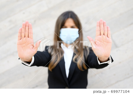 Coronavirus concept. Woman wearing mask for protection from disease, shows stop gesture with hands 69977104