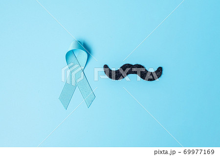 November Prostate Cancer Awareness month, light Blue Ribbon with mustache on wooden background for supporting people living and illness. Farther, international men day and World cancer day concept 69977169