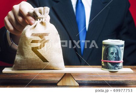 Businessman puts indian rupee money bag on the 69977753