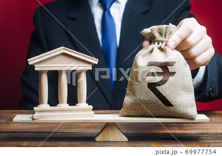 Businessman puts a indian rupee money bag on 69977754