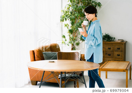 女性　リビング　立つ　スマホ　コーヒー 69979304