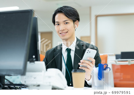 オフィスで仕事をする笑顔の若いビジネスマン オフィスで仕事をする笑顔の若いビジネスマン 69979591