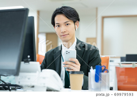 オフィスで仕事をする笑顔の若いビジネスマン オフィスで仕事をする笑顔の若いビジネスマン 69979593