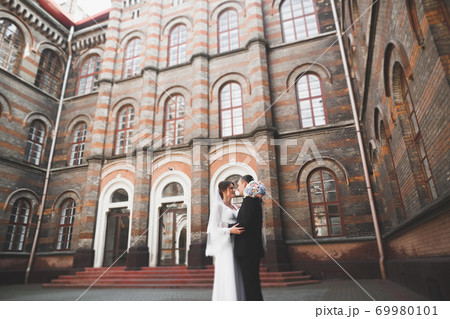 Gorgeous wedding couple walking in the old city of Lviv Gorgeous wedding couple walking in the old city of Lviv 69980101