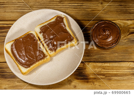 Two slices of bread with delicious chocolate hazelnut spread on wooden table. Top view 69980665