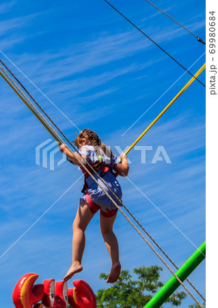 Little girl jumping on bungee trampoline 69980684