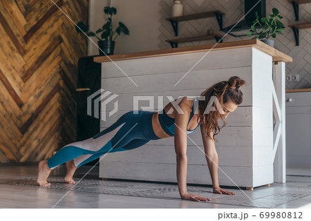 Young woman warming up and doing push ups at home 69980812