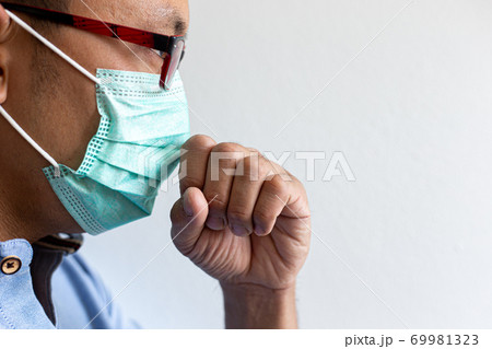 The young man has headache coughing and sneezing which is caused by the infection of the COVID-19 virus or the CORONA virus By wearing a mask to prevent the germs from spreading to those around you, H 69981323