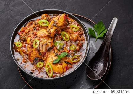 A Chicken Patiala in black bowl on dark slate table top. Murg Patiala is indian cuisine curry dish A Chicken Patiala in black bowl on dark slate table top. Murg Patiala is indian cuisine curry dish 69981550