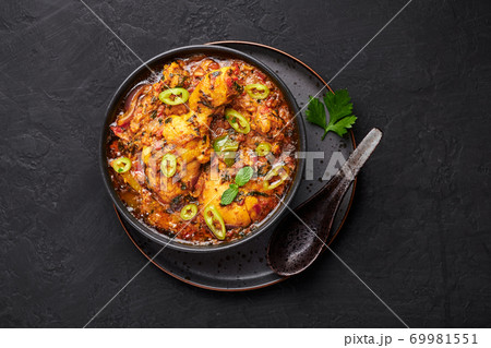 A Chicken Patiala in black bowl on dark slate table top. Murg Patiala is indian cuisine curry dish A Chicken Patiala in black bowl on dark slate table top. Murg Patiala is indian cuisine curry dish 69981551