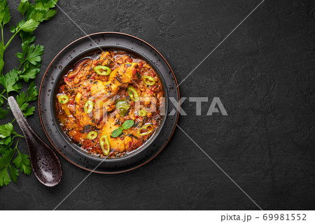 A Chicken Patiala in black bowl on dark slate table top. Murg Patiala is indian cuisine curry dish A Chicken Patiala in black bowl on dark slate table top. Murg Patiala is indian cuisine curry dish 69981552