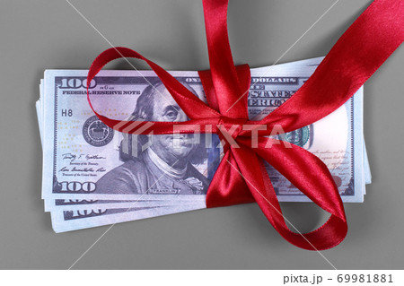 Hundred dollar bill tied with red bow on grey background. Money, gift wrapped in red bow and ribbon, US currency, cash, business success, bonus, monetary prize, luck in the game concept 69981881