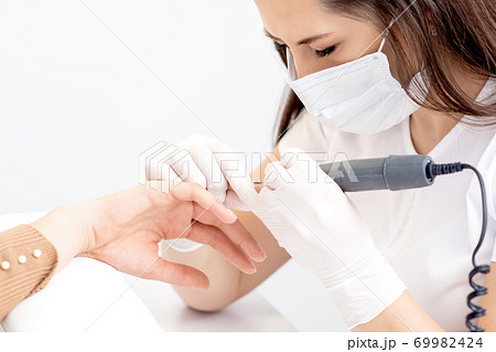 Manicure master uses an electric nail machine 69982424