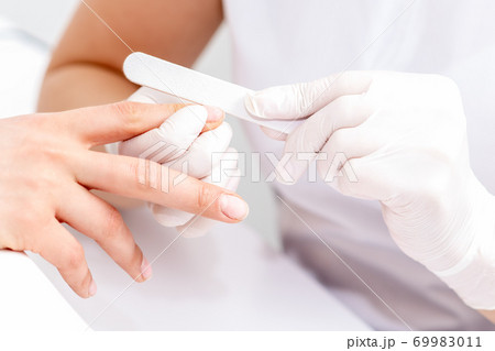 Young woman receiving manicure by nail file Young woman receiving manicure by nail file 69983011