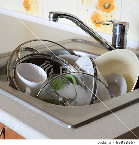 Dirty dishes and unwashed kitchen appliances filled the kitchen sink Dirty dishes and unwashed kitchen appliances filled the kitchen sink 69983867