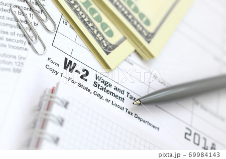 The pen, notebook and dollar bills is lies on the tax form W-2 Wage and Tax Statement. The time to pay taxes 69984143