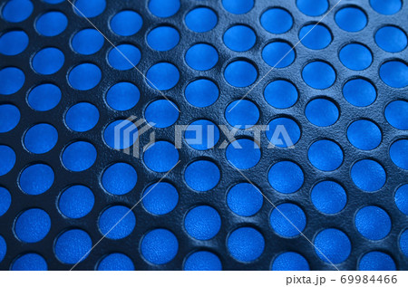 Black metal computer case panel mesh with holes on blue background. Abstract close up image 69984466
