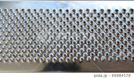 A fragment of a metal chrome grater close-up. Texture of blades for grinding food A fragment of a metal chrome grater close-up. Texture of blades for grinding food 69984578