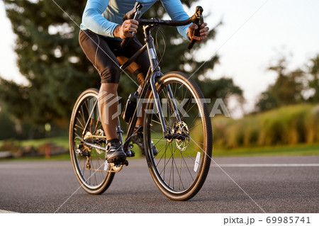 Cropped shot of a road bicycle racer in sportswear cycling in park on a summer day Cropped shot of a road bicycle racer in sportswear cycling in park on a summer day 69985741