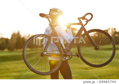 Strong athletic man in sportswear holding a bicycle while standing in park at sunset, cycling outdoors and enjoying amazing nature view Strong athletic man in sportswear holding a bicycle while standing in park at sunset, cycling outdoors and enjoying amazing nature view 69985744