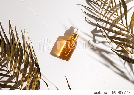 White, orange and black serum bottles on white background. Trending golden branches of palm. Cosmetic mockup. Place to insert text, images. Top view. Flat lay. White, orange and black serum bottles on white background. Trending golden branches of palm. Cosmetic mockup. Place to insert text, images. Top view. Flat lay. 69985778