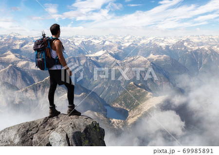 Adventurous Man Hiker on top of a Steep Rocky Cliff 69985891