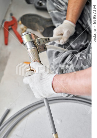 connection heating pipes to white Radiator in a new apartment under construction. Work As A Plumber, mounting water heating radiator on the white wall indoors connection heating pipes to white Radiator in a new apartment under construction. Work As A Plumber, mounting water heating radiator on the white wall indoors 69987394