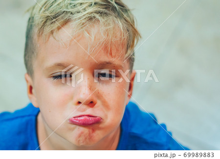 Closeup portrait boy mischievous cute blond close blue eyes, stuck out lip gesture of unwillingness, making freckles face play in mood. Funny photo, happiness lifestyle. Daycare, childhood, behaviour Closeup portrait boy mischievous cute blond close blue eyes, stuck out lip gesture of unwillingness, making freckles face play in mood. Funny photo, happiness lifestyle. Daycare, childhood, behaviour 69989883