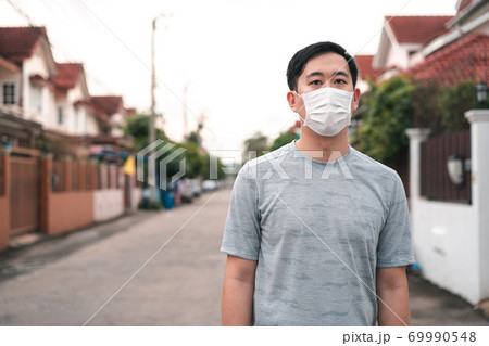 Young Asian man wearing a face protective mask in front of his house outdoors. Wearing a face mask before leaving home 69990548