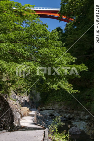 秋田県湯沢市の観光名所小安峡の通路と木と湯気と赤い橋の写真素材