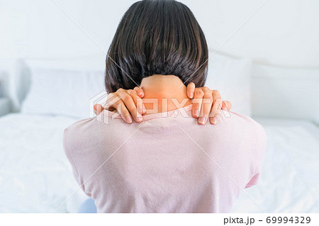 Beautiful asian woman suffering Shoulder ache pain tired sit on bed. bedroom background. back view Beautiful asian woman suffering Shoulder ache pain tired sit on bed. bedroom background. back view 69994329