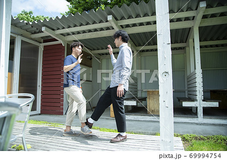 足を突き合わせて挨拶する若い男性 69994754