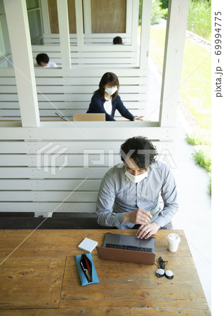 テラス席で仕事をする男女 69994775