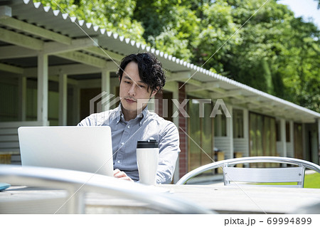 テラス席で仕事をするミドルの男性 69994899