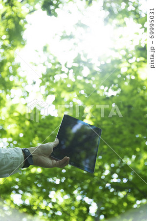森の中でタブレットPCを持つミドル男性の手元 森の中でタブレットPCを持つミドル男性の手元 69995031