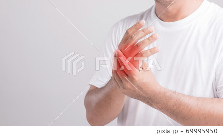 Close up man touching palm and feeling a pain. Studio shot isolated on grey background with copy space for text Close up man touching palm and feeling a pain. Studio shot isolated on grey background with copy space for text 69995950