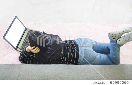 Young asian woman wore black knitwear, lying on pink carpet ,work online lifestyle,relax at home with coffee mug,home working laptop,work from home 69996060