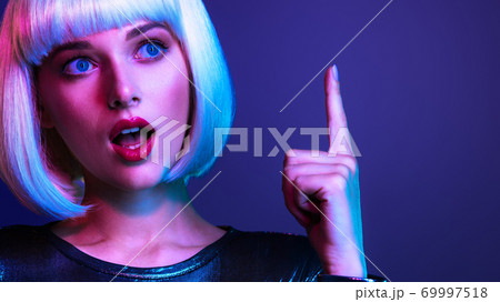 Surprised Face of glamour girl with an idea concept. Young beautiful woman with a shocked face and forefinger up. Wondered female face in a white wig. Emotional person. Surprised Face of glamour girl with an idea concept. Young beautiful woman with a shocked face and forefinger up. Wondered female face in a white wig. Emotional person. 69997518