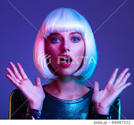 Surprised  Face of glamour girl. Wondered female face in a white wig. Young beautiful woman with a shocked face. Art portrait  of  an young attractive woman with hands at face. Emotional person. 69997522