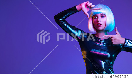Full-length portrait of the beautiful woman with lifted hands up near face. Art portrait of an young attractive model. Fantasy style. Glamour fashion girl. Stylish blonde in shiny dress. Full-length portrait of the beautiful woman with lifted hands up near face. Art portrait of an young attractive model. Fantasy style. Glamour fashion girl. Stylish blonde in shiny dress. 69997539