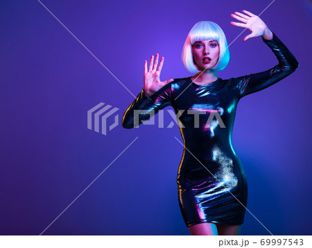 Full-length portrait of the beautiful woman with lifted hands up near face. Art portrait of an young attractive model. Fantasy style. Glamour fashion girl. Stylish blonde in shiny dress. Full-length portrait of the beautiful woman with lifted hands up near face. Art portrait of an young attractive model. Fantasy style. Glamour fashion girl. Stylish blonde in shiny dress. 69997543