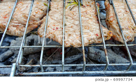 Beef cooked in an outdoor coal barbecue. Barbecue on a metal grill on hot coals. Beef cooked in an outdoor coal barbecue. Barbecue on a metal grill on hot coals. 69997734